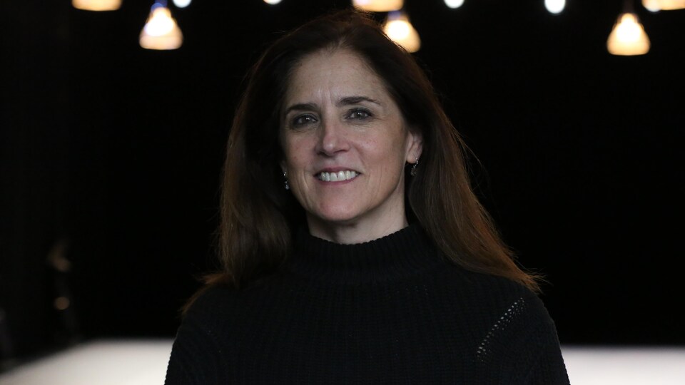 Une femme habillée en noir sourit à la caméra.