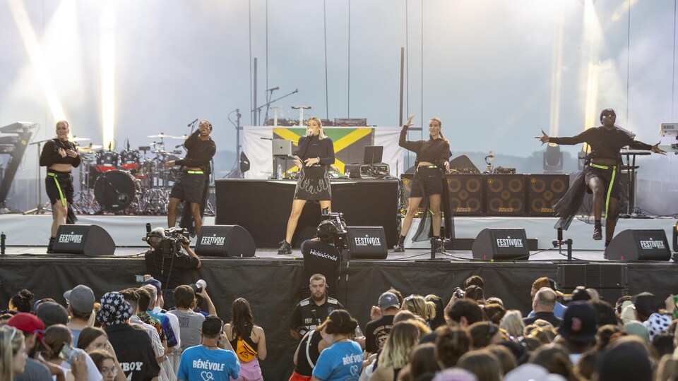 Lawrence Nierbon sings on stage, accompanied by four dancers. 