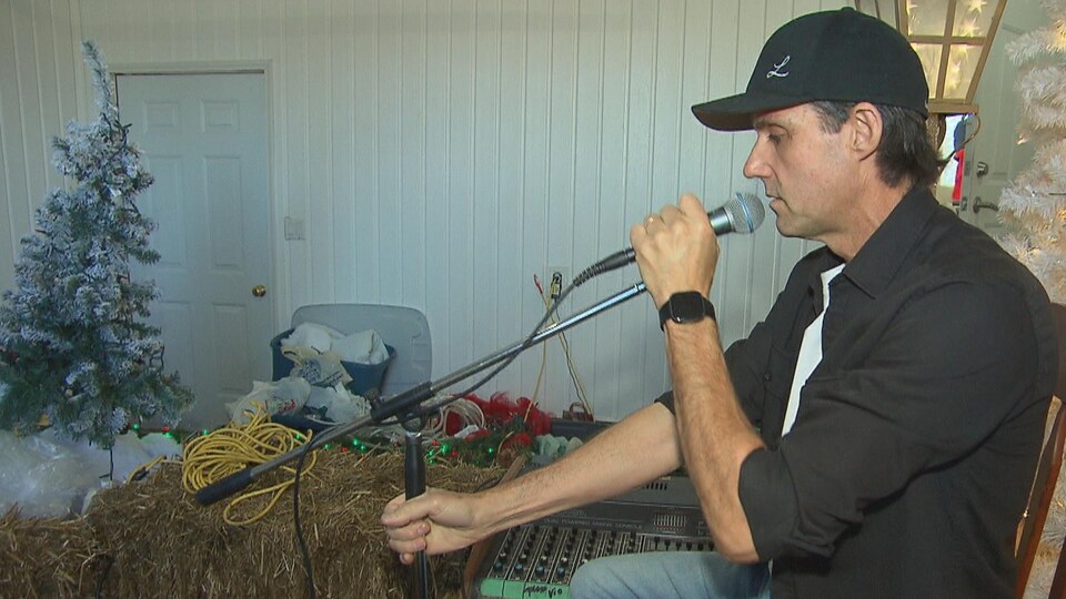 Le chanteur ajuste un pied de micro dans un décor de Noël.