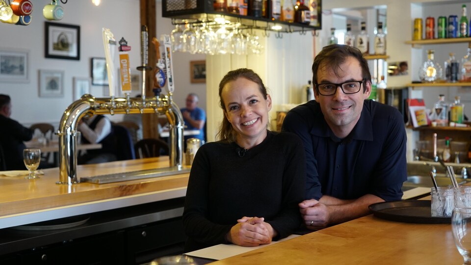 Un homme et une femme se tiennent devant un bar dans un restaurant.