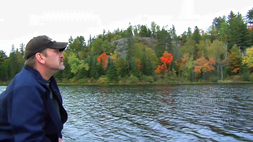 M Falldien pose devant un lac à l'automne, il regarde au loin.