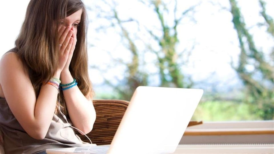 Une jeune fille voit un acte choquant sur un écran d'ordinateur. 