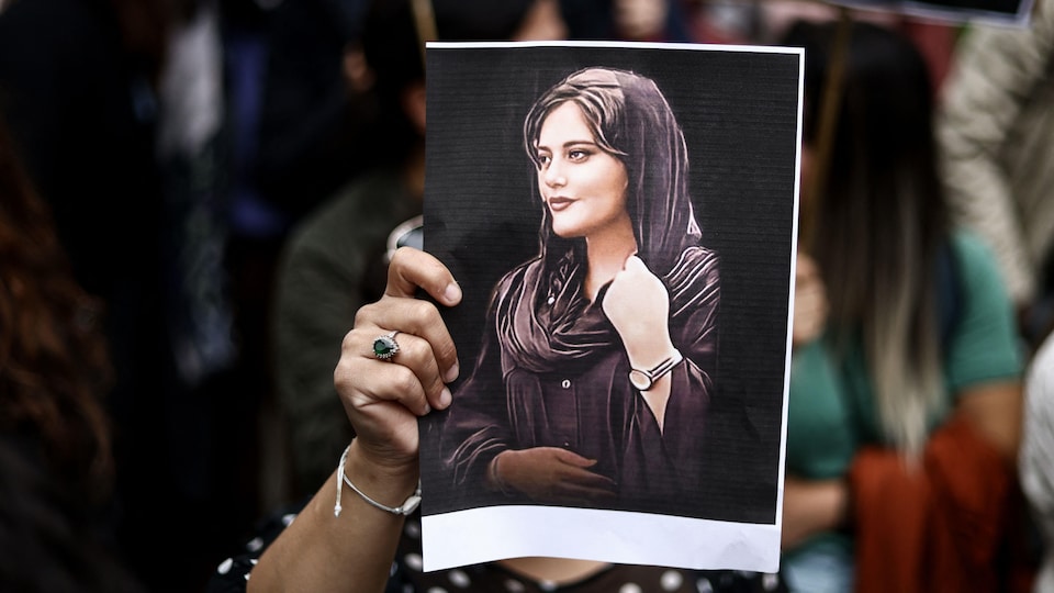 Une personne tient un portrait de Mahsa Amini.