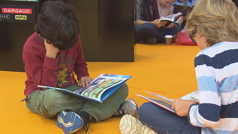 Des enfants lisent au salon du livre de l'Estrie.