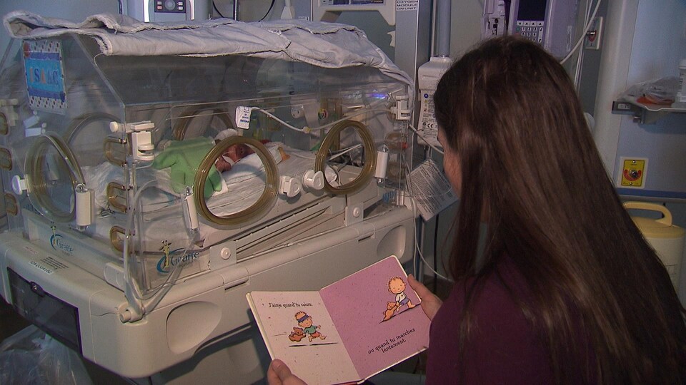 Une femme lit doucement un conte à un bébé prématuré.