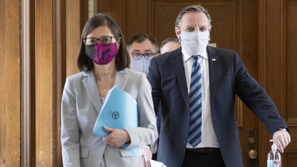 François Legault, Danielle McCann et Horacio Arruda marchent dans les corridors de l'Assemblée nationale. Ils portent tous les trois un masque.