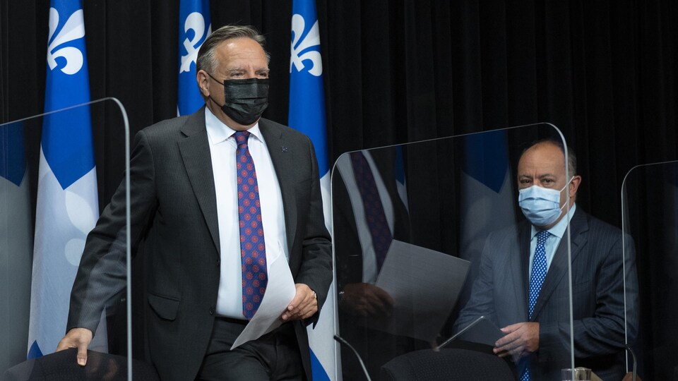 MM. Legault et Dubé portant le masque et arrivant à la conférence de presse.