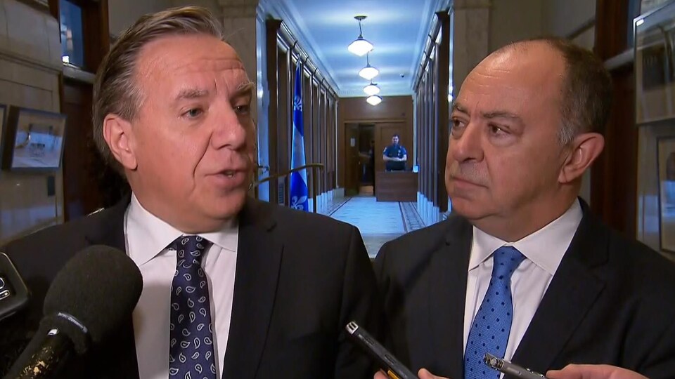 François Legault et Christian Dubé devant des micros, dans un corridor de l'Assemblée nationale.