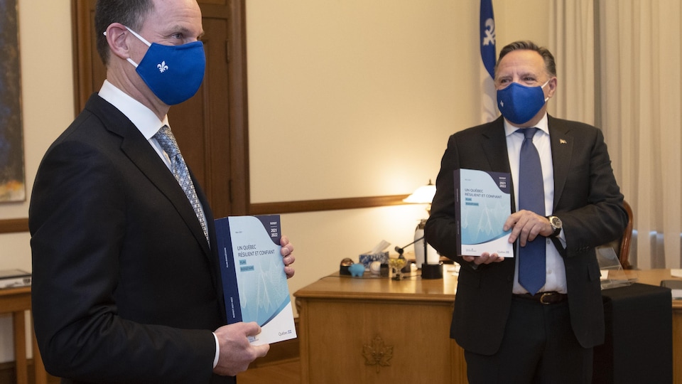 Les deux hommes tiennent des exemplaires du budget.