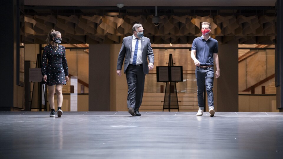 Masqués, le premier ministre et les comédiens marchent dans les couloirs de la Place des Arts.