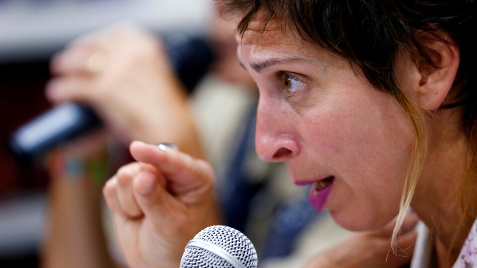 Une femme de profil parle dans un micro.