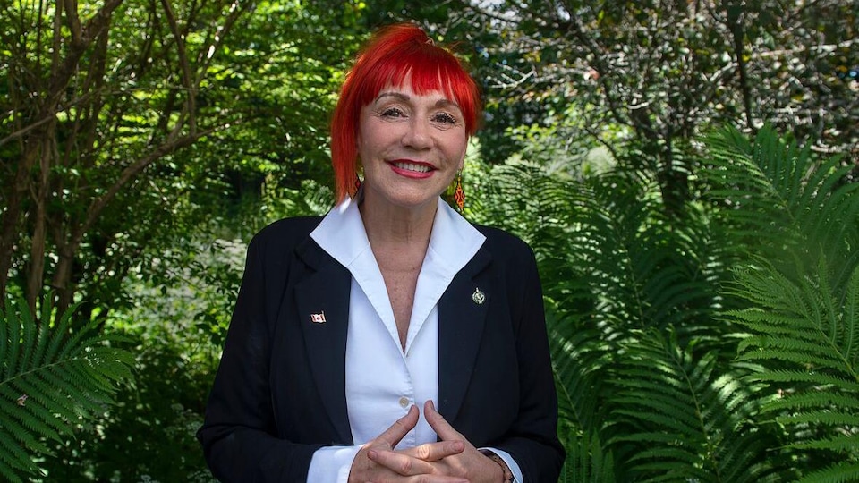 Lenore Zann devant des plantes vertes.