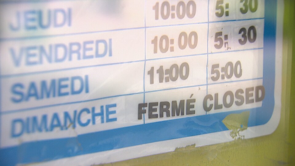 L'horaire d'un commerce posé dans une vitrine fermé le dimanche.