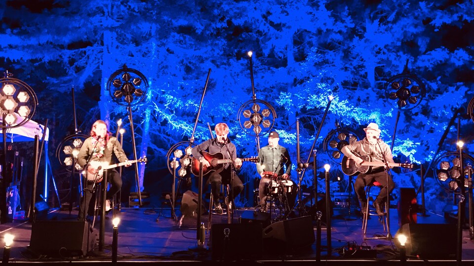 les membres du groupe de musique sont sous les arbres à l'extérieur.
