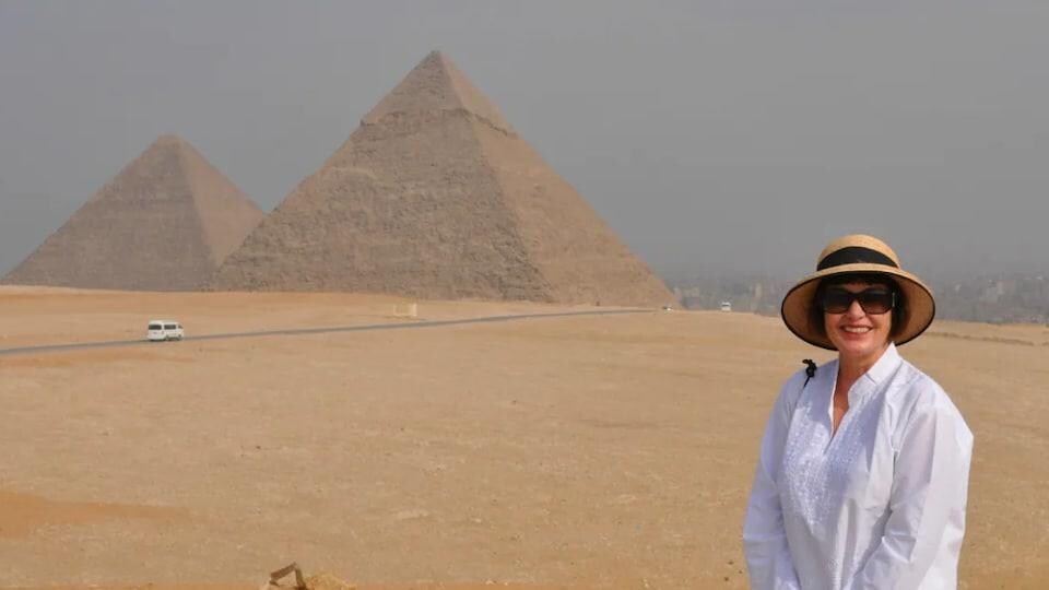 Lesley Keyter est debout devant un paysage désertique et deux pyramides.