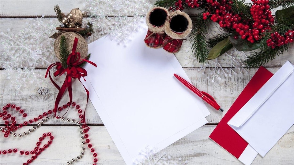 Une lettre de souhaits. Un stylo rouge et une feuille de papier reposent sur un bureau.