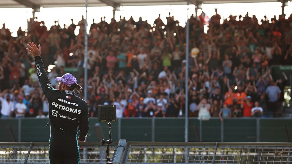 Le pilote britannique, casquette sur la tête, escalade un grillage pour saluer la foule après avoir inscrit le meilleur temps des qualifications.