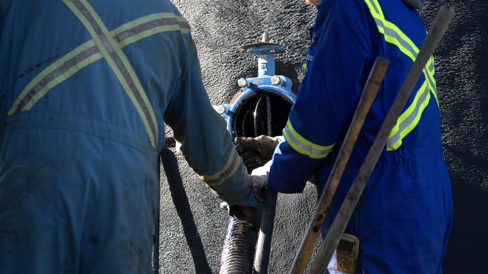 Deux ouvriers sont en train de nettoyer un puits de pétrole abandonné près de Frog Lake, en Alberta, en octobre 2022.