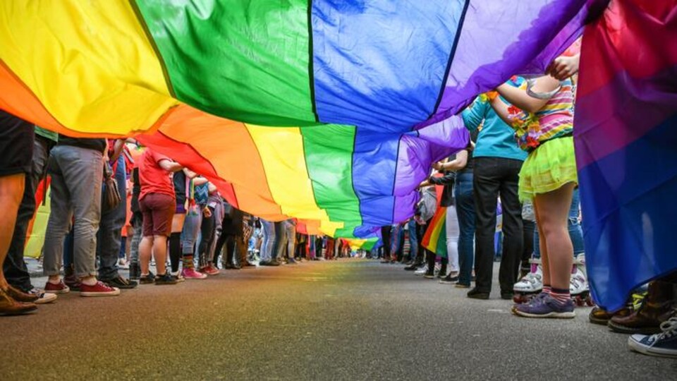 Des personnes tiennent le drapeau arc-en-ciel LGBT.