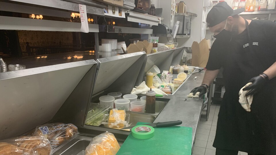 Un employé nettoie son comptoir à sandwich.