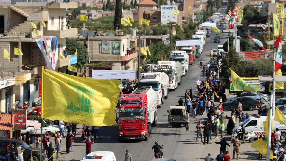 Un convoi de camions-citernes dans une ville, où des drapeaux sont hissés.