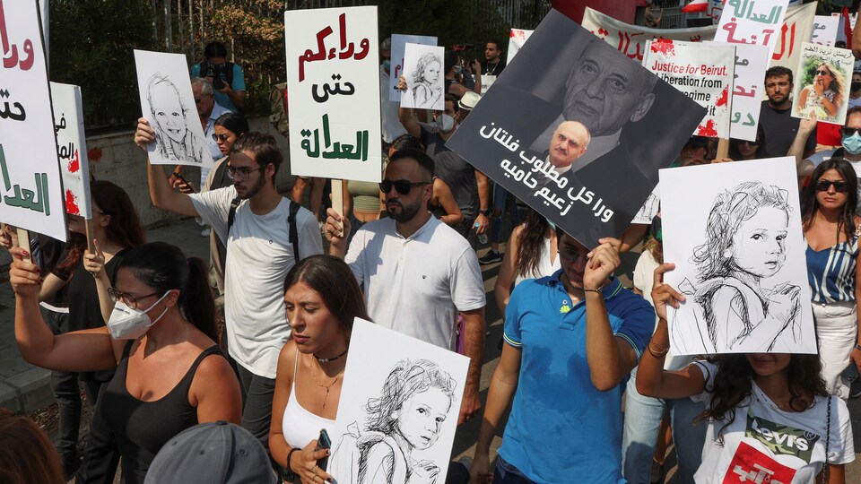 Des Libanais manifestent dans la rue avec des pancartes. 