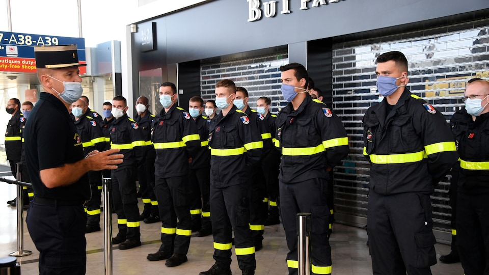 Des membres de la Sécurité civile française portant des masques, à l'aéroport de Roissy.