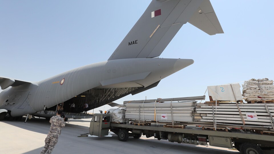 Des travailleurs chargent du matériel à bord d’un avion qatari.
