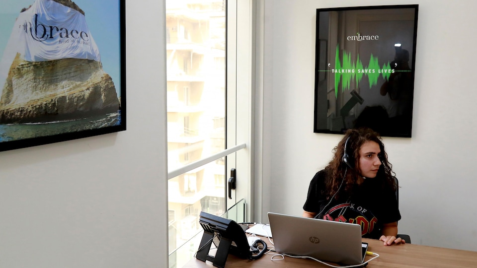 Une volontaire de Embrace Lifeline prend un appel avec un casque d'écoute, dans les bureaux de l'organisme à Beyrouth.