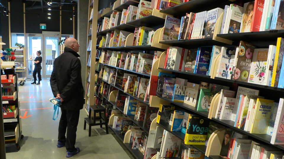 Un client cherche un livre dans un rayon de la librairie Laliberté.