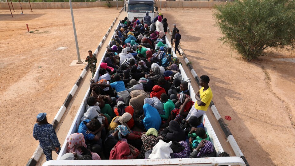Des migrants arrivent par camions dans un camp de détention en Libye.