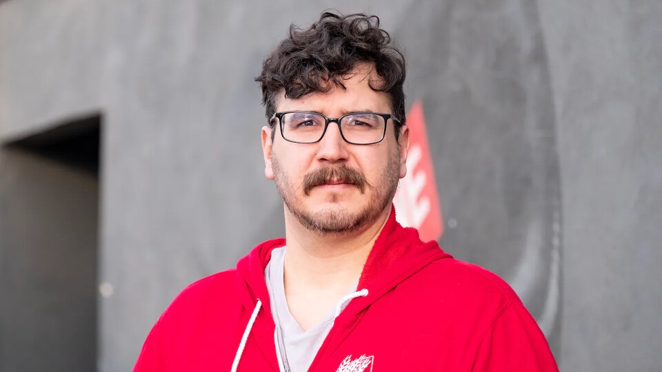 Un homme porte des lunettes de vue et une moustache.