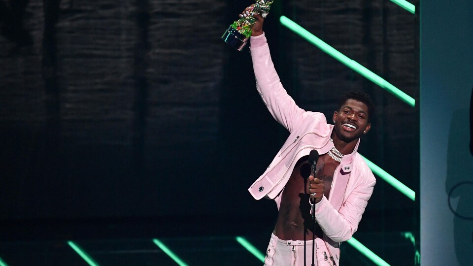 Lil Nas X sur scène lève son prix dans les airs en signe de victoire.