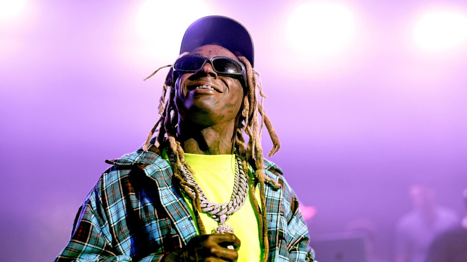 Lil Wayne sourit en regardant au-dessus de la caméra.