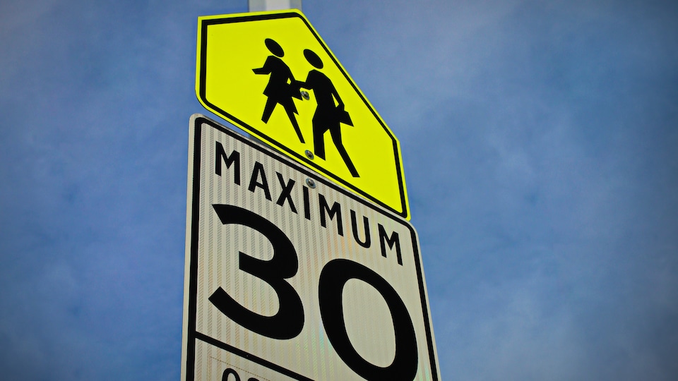 Panneau de signalisation indiquant une limite de vitesse de 30 km/h dans une zone scolaire.