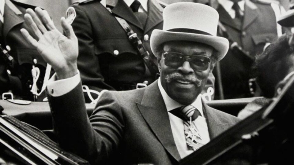 Le portrait d'un homme qui porte un chapeau et des lunettes dans une voiture