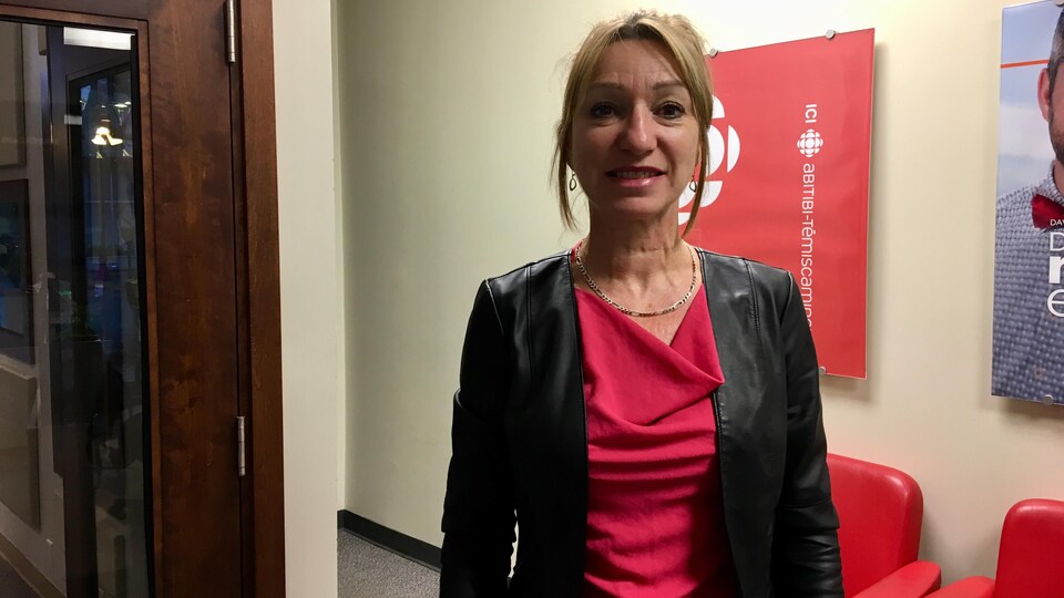 Linda Turcotte pose devant l'affiche de Radio-Canada Abitibi-Témiscamingue,