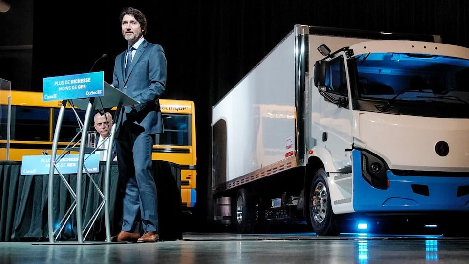 Justin Trudeau debout derrière un lutrin et devant un camion électrique.