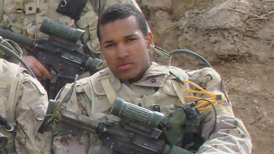 Lionel Desmond assis, en uniforme et avec son arme.