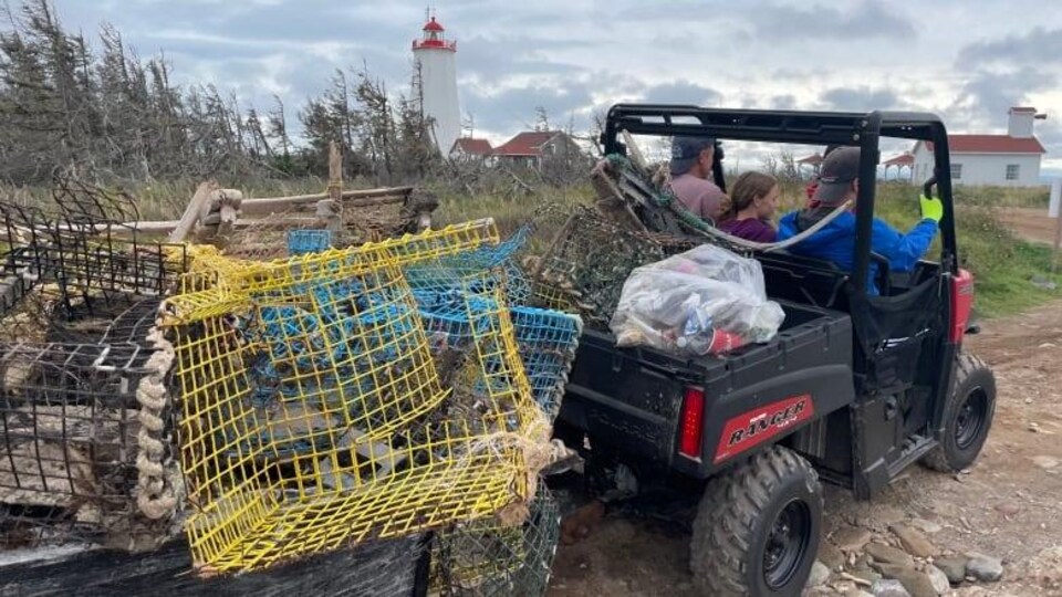 Des gens à bord d'un VTT ramassent des cages à homards, placés à l'arrière du véhicule motorisé.