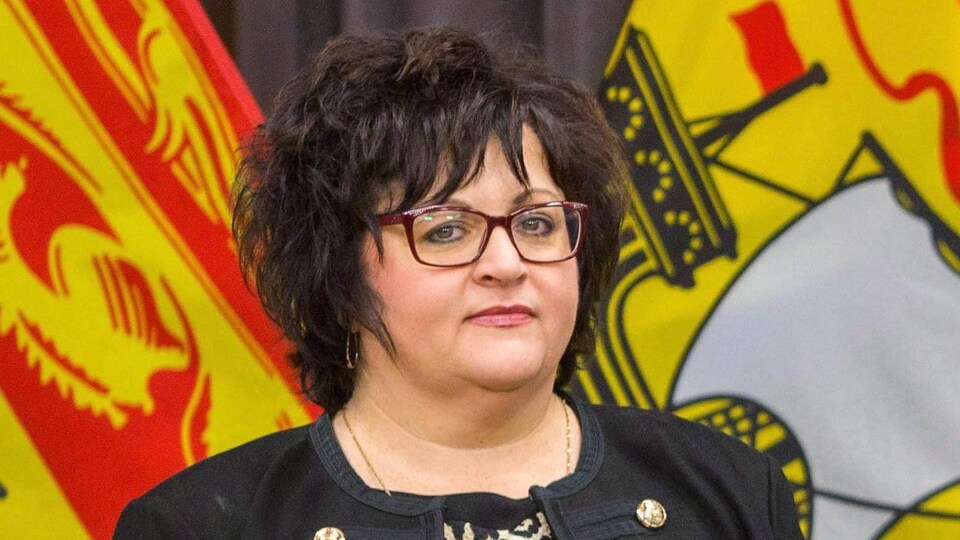 Lisa Harris debout devant des drapeaux du Nouveau-Brunswick.