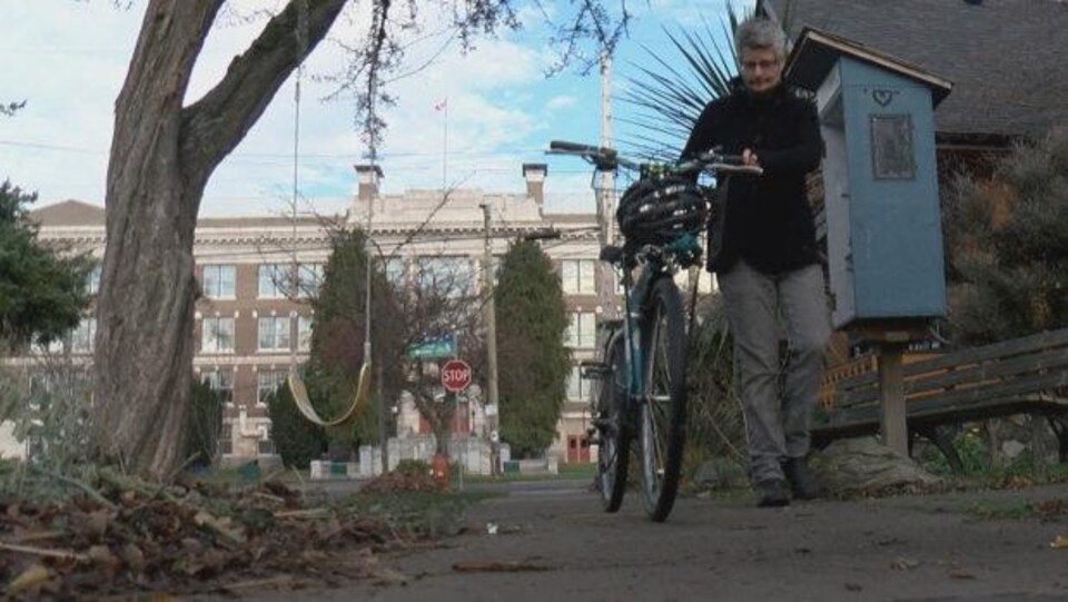 La mairesse de Victoria, Lisa Helps, marche sur un trottoir en tenant le guidon de son vélo
