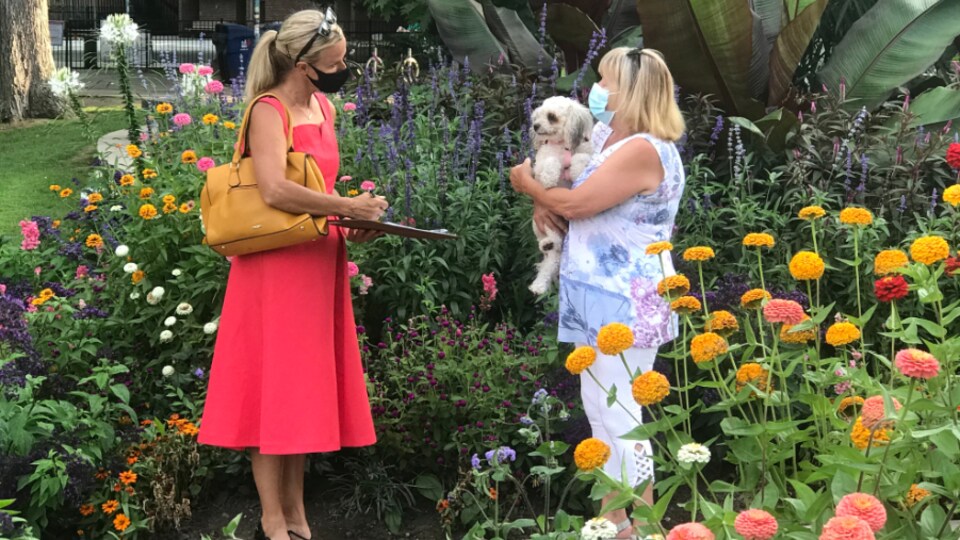 Lisa Robinson écoute une électrice dans un parc fleuri.