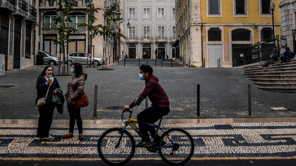 Un homme masqué fait du vélo à Lisbonne.