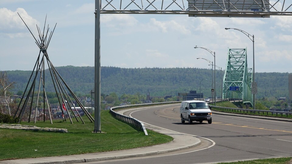 Une voiture vient de traverser le pont Van Horne. À gauche, le tipi traditionnel représentant Listuguj.
