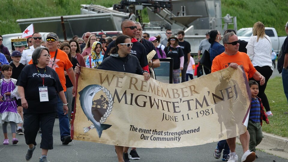 Des chefs autochtones tiennent une bannière lors d'une marche dans les rues de Listuguj.