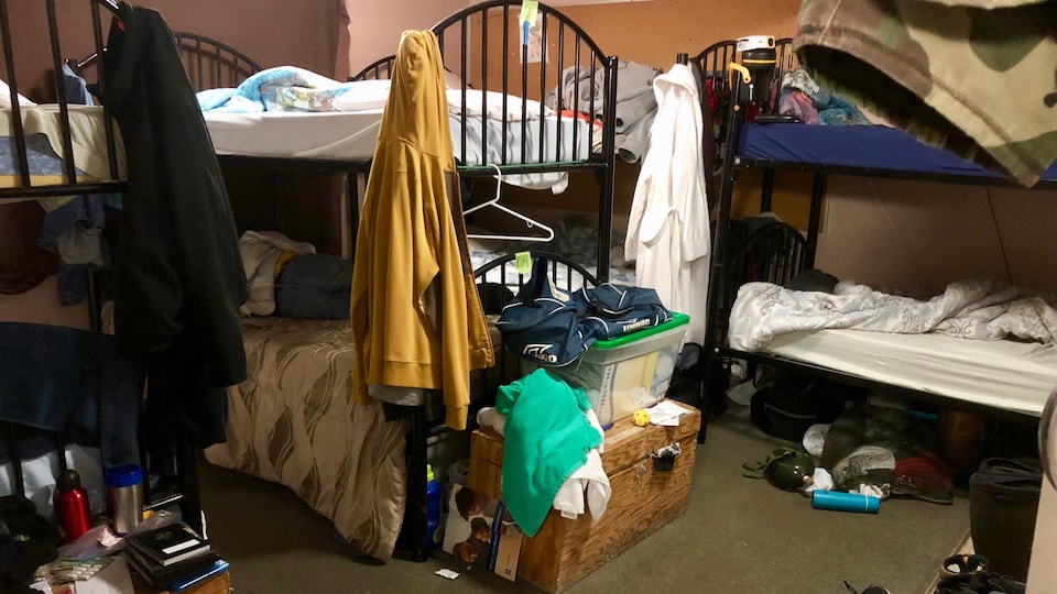 Des lits s'empilent dans un dortoir de centre d'accueil pour sans-abri.