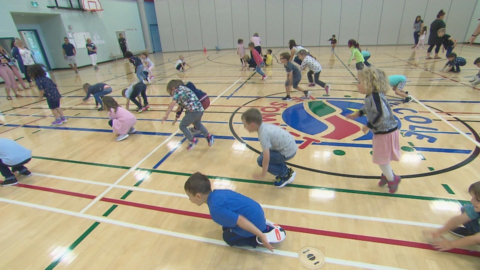 Des enfants qui font des exercices d'échauffement dans un gymnase.
