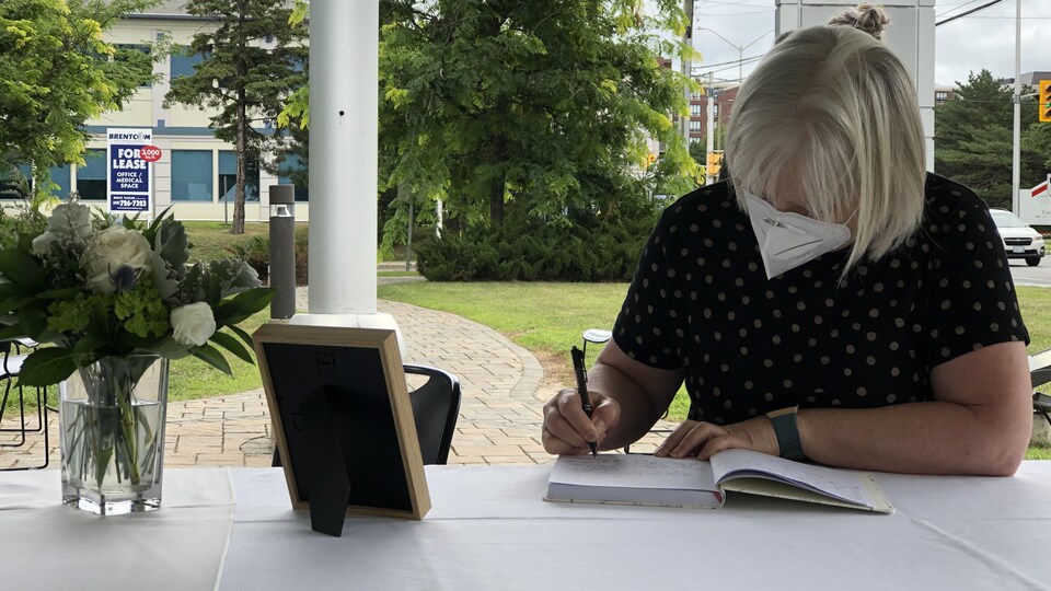 Une femme écrit dans un livre. 