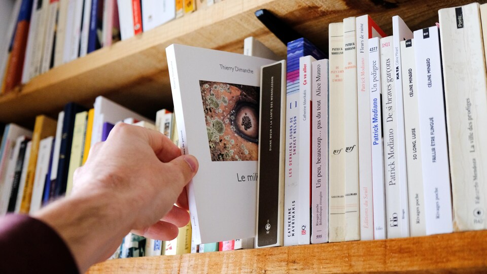 Un livre est sélectionné dans une bibliothèque.